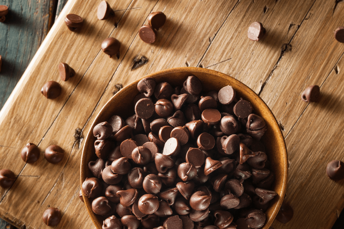 Chocolate chips in a bowl on a wooden table.