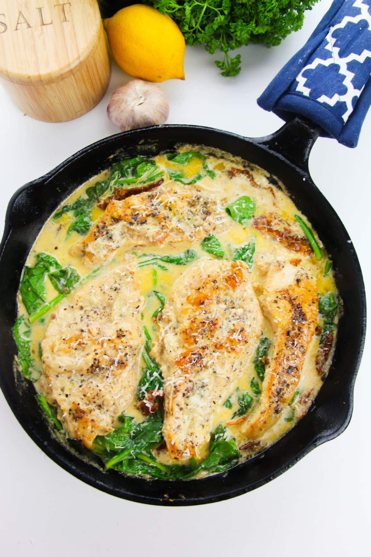 Cooked Tuscan chicken in a skillet, garnished with parmesan cheese.