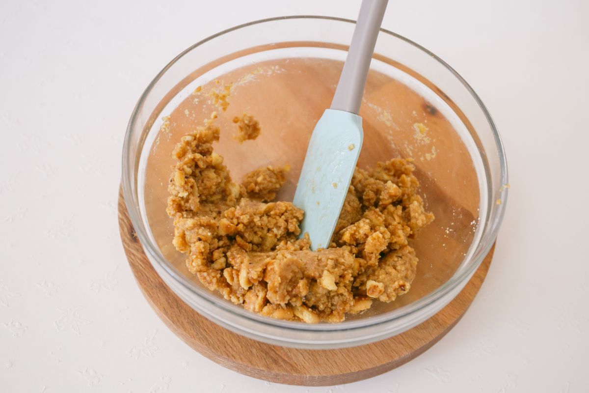 Crust mixture with a blue spatula in a glass mixing bowl.