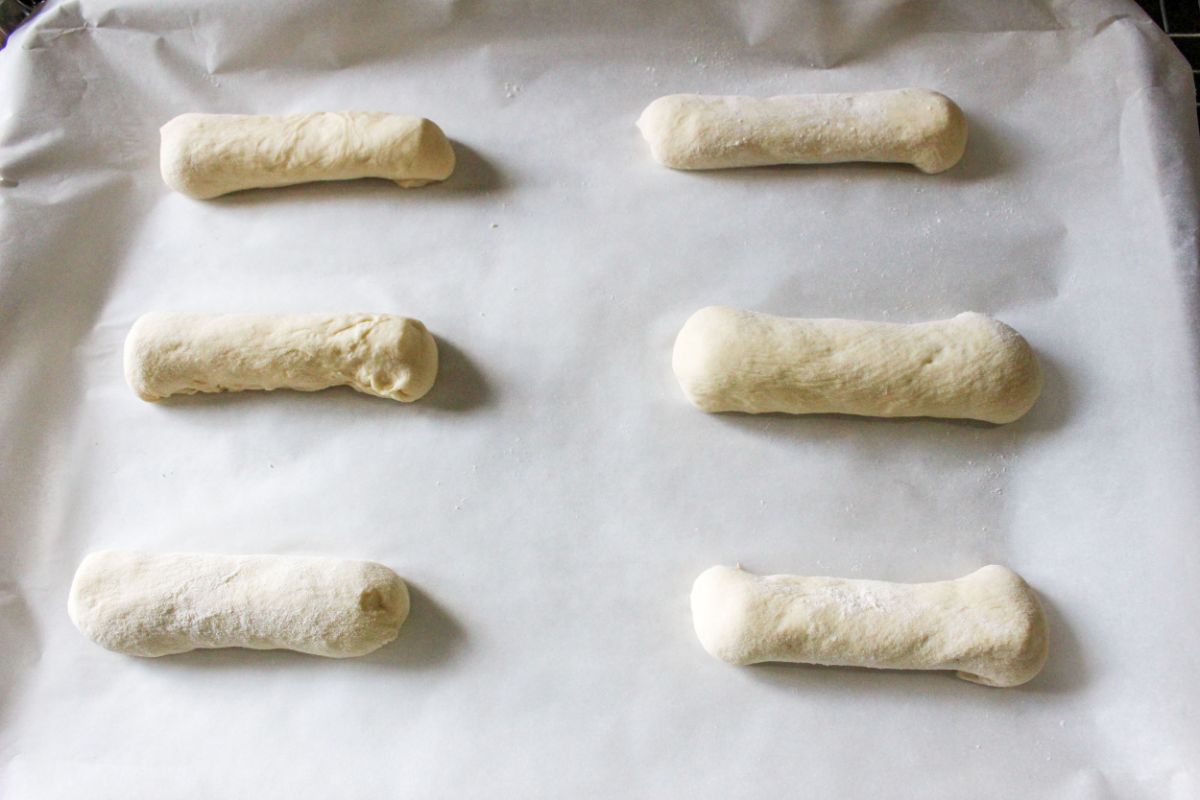 A baking sheet with cheese stuffed breadsticks on it.