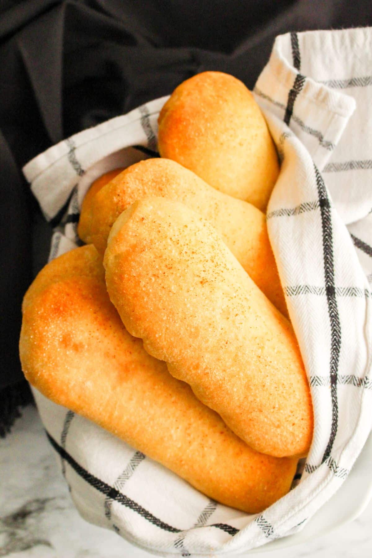 Cheese Stuffed Breadsticks in a white bowl with cloth on a marble counter.