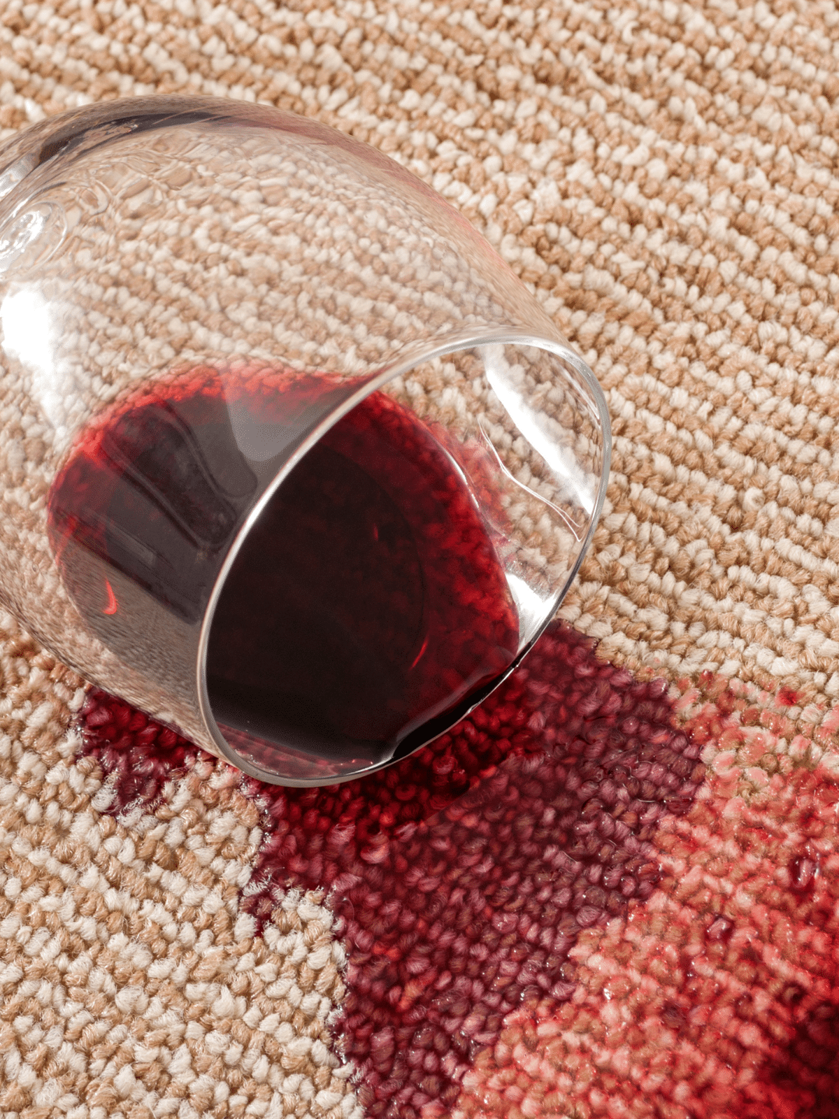 A spilled glass of red wine on a carpet.