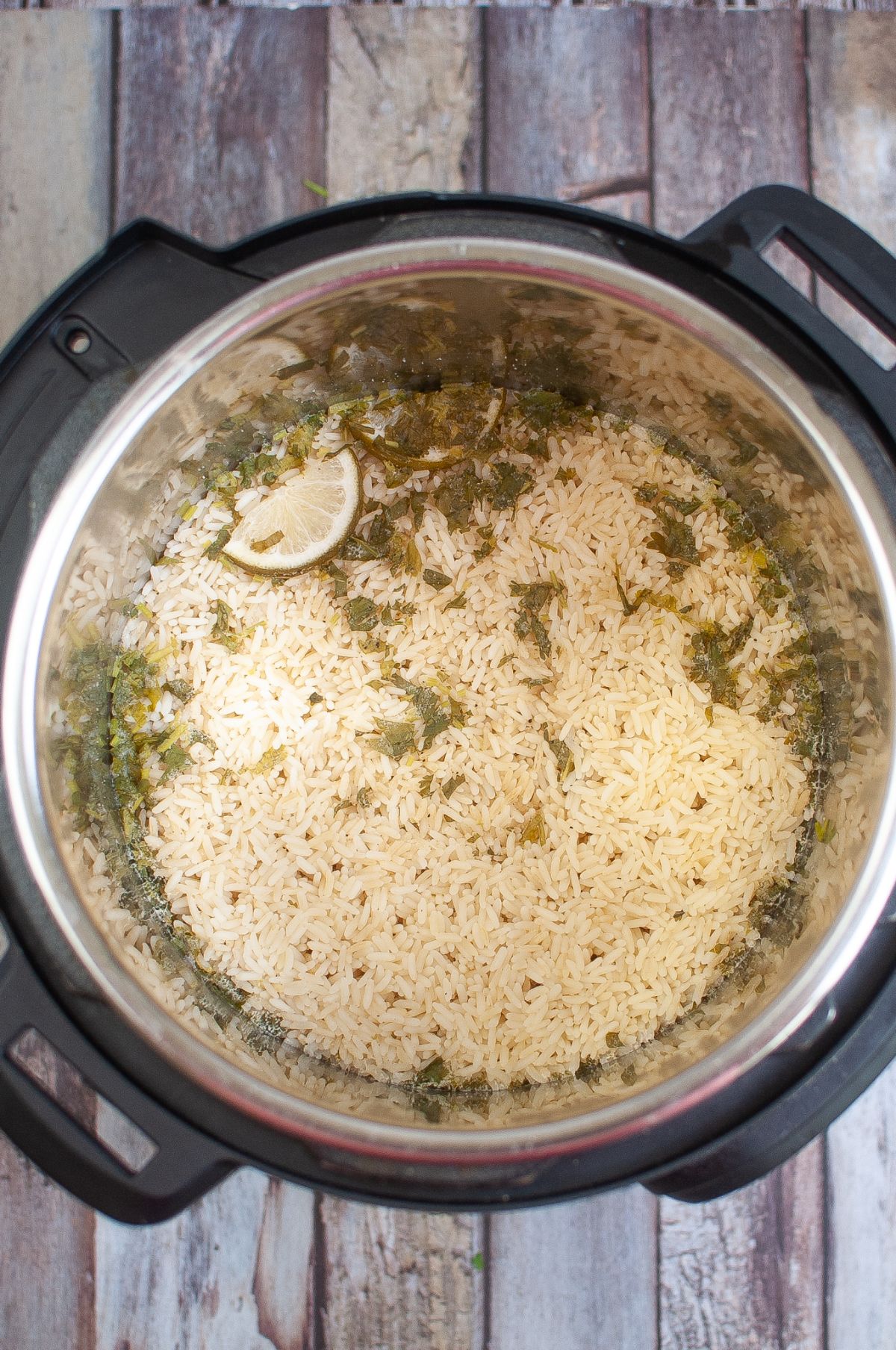 Cooked rice pilaf in an instant pot on a wooden table.