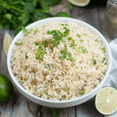 Mexican rice with Instant Pot Rice Pilaf, served in a white bowl garnished with limes and cilantro.