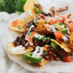 Pulled pork nachos served on a white plate.