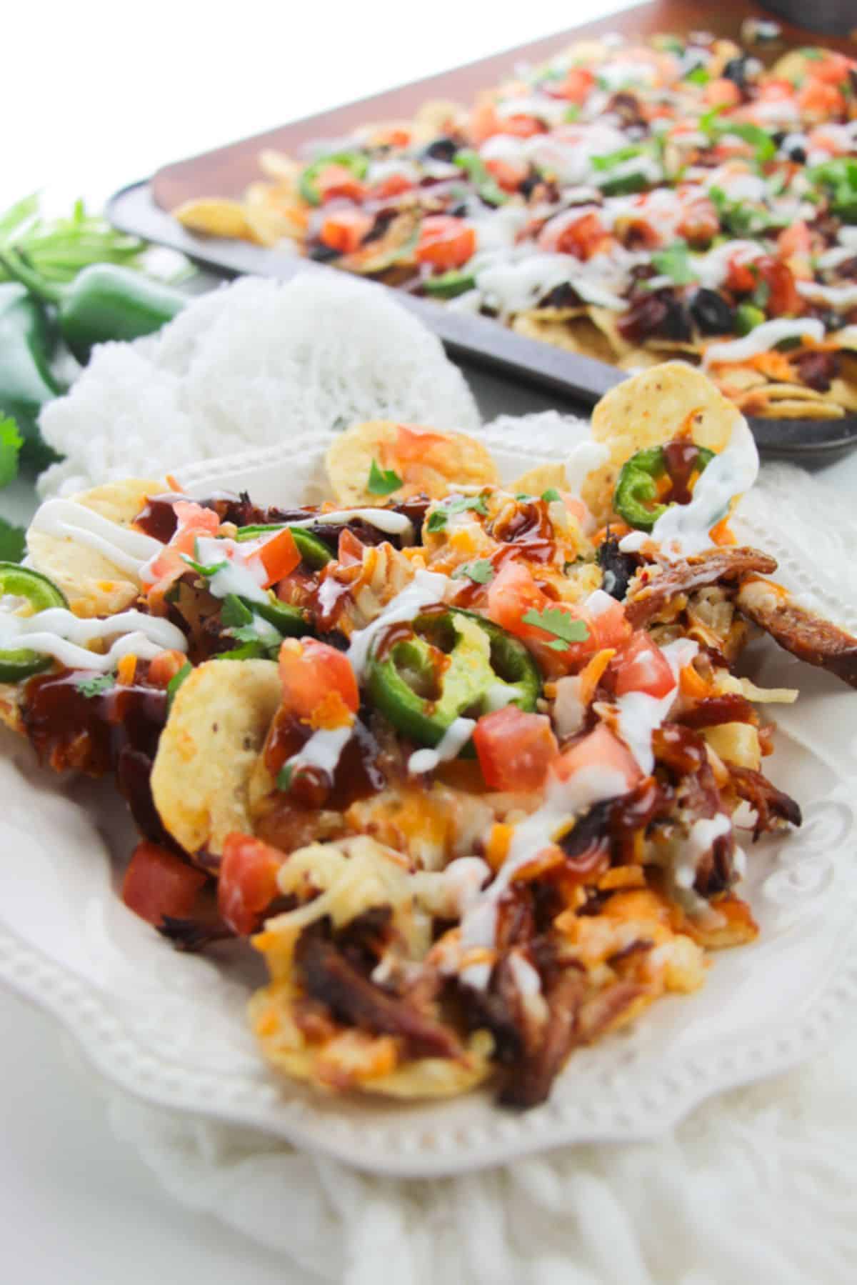 close up of Pulled pork nachos served on a white plate.