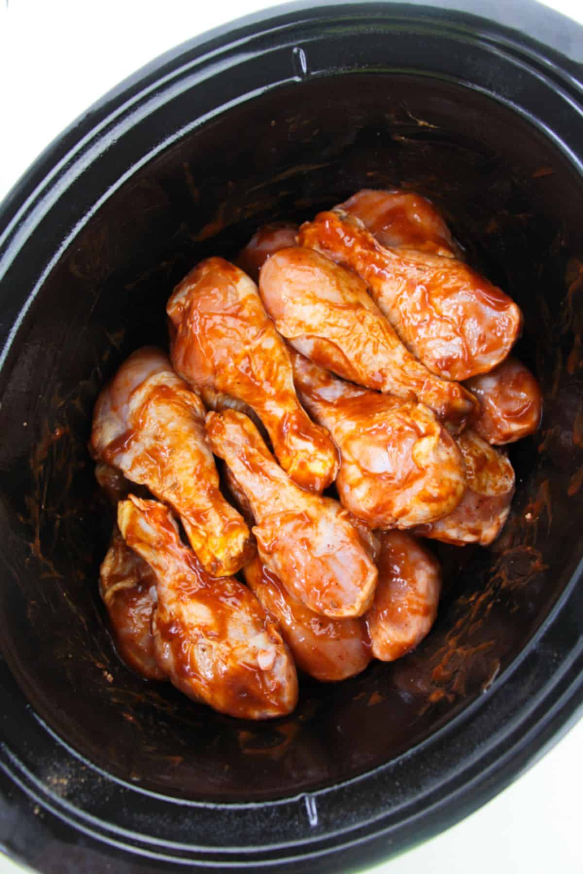 Chicken legs coated with bbq sauce inside the slow cooker.