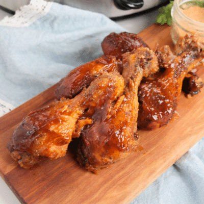 Slow Cooker BBQ Chicken Legs on a wooden cutting board.