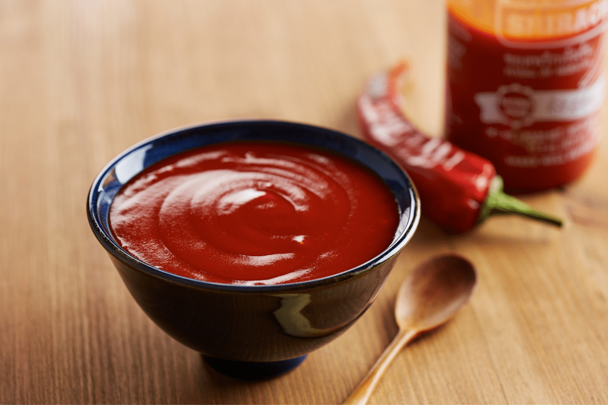 Sriracha sauce in a bowl next to a spoon.