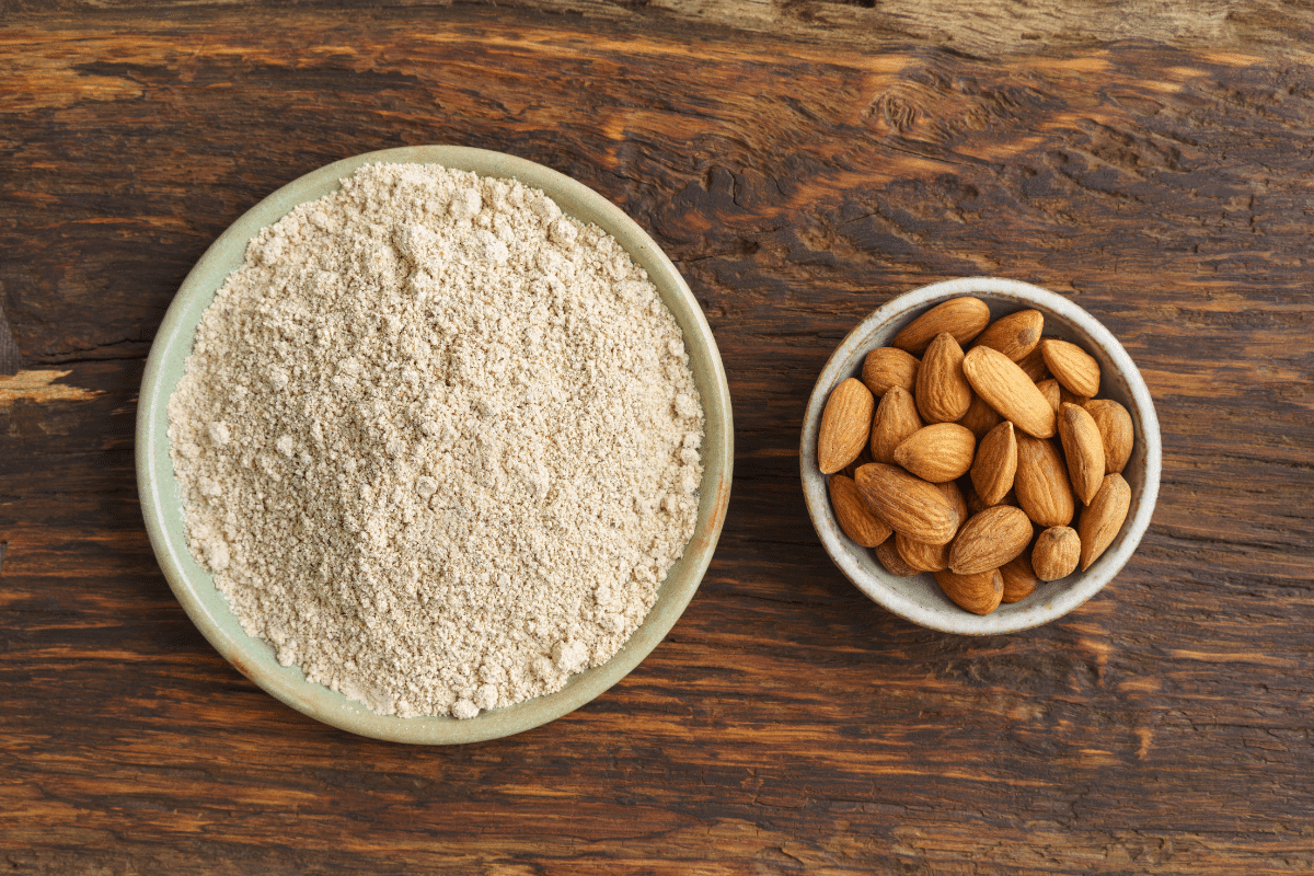 Almond flour and almonds, a substitute for coconut flour, in a bowl on a wooden table.