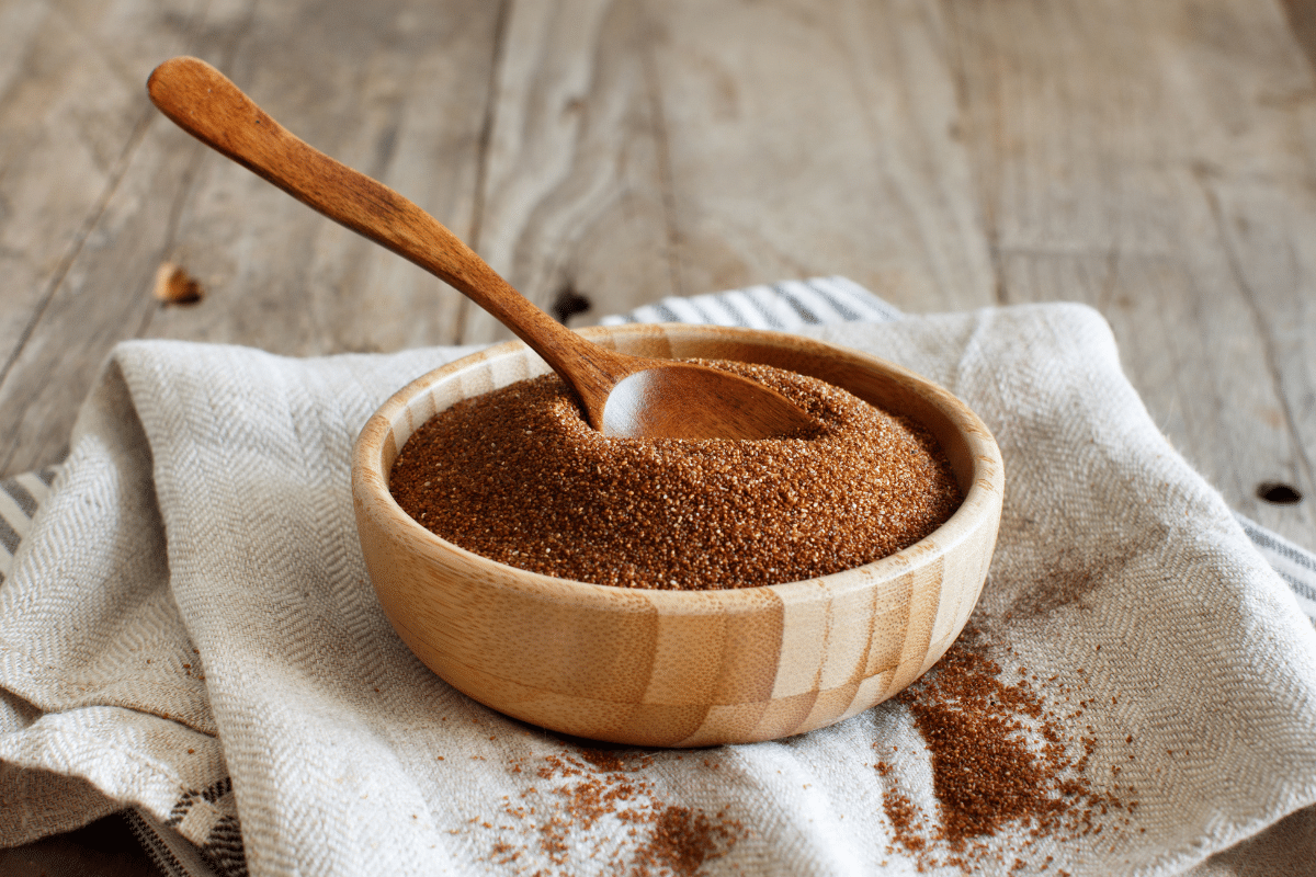 Teff in a wooden bowl with wooden spoon in it.
