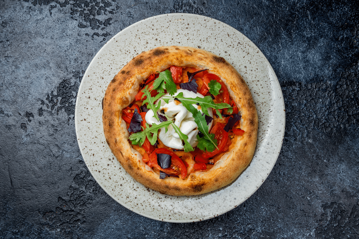 A pizza topped with burrata cheese on a plate.