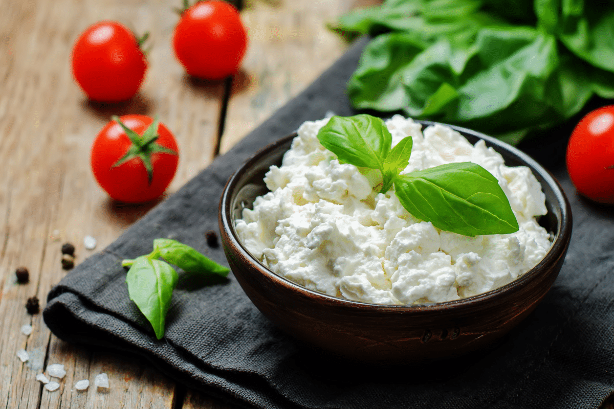 Ricotta cheese in a bowl with tomatoes and basil.