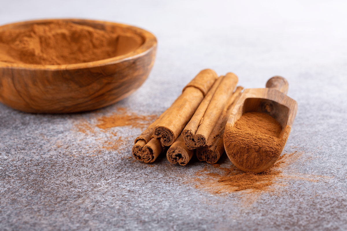 Cinnamon sticks and powder in a wooden spoon and bowl.