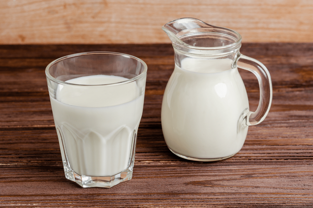 Regular milk in a glass and glass pitcher.
