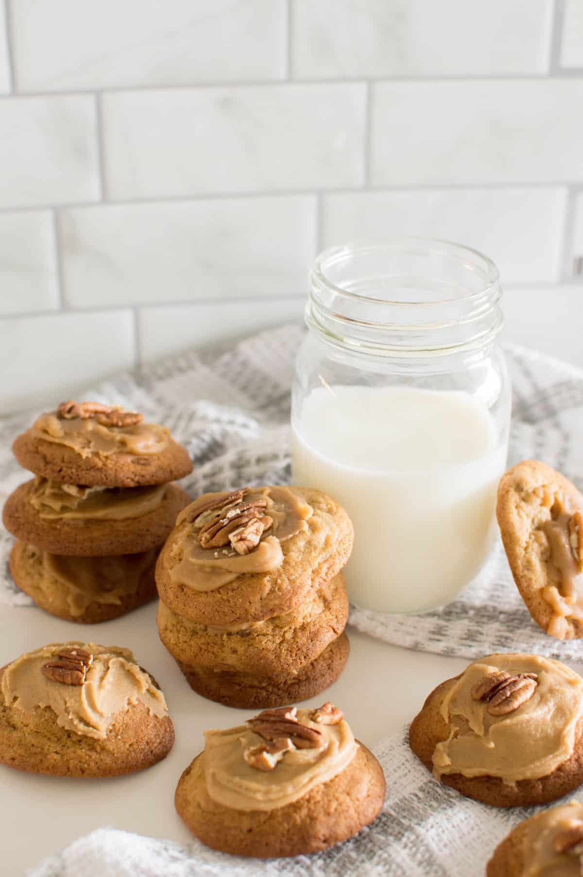 Brown Sugar Pecan Cookies on a white and grey cloth with a glass of milk on the side.