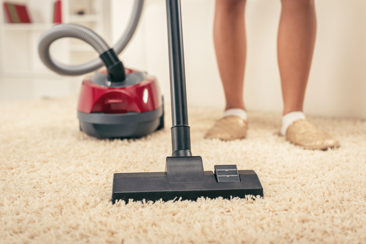 A woman using a vacuum cleaner.