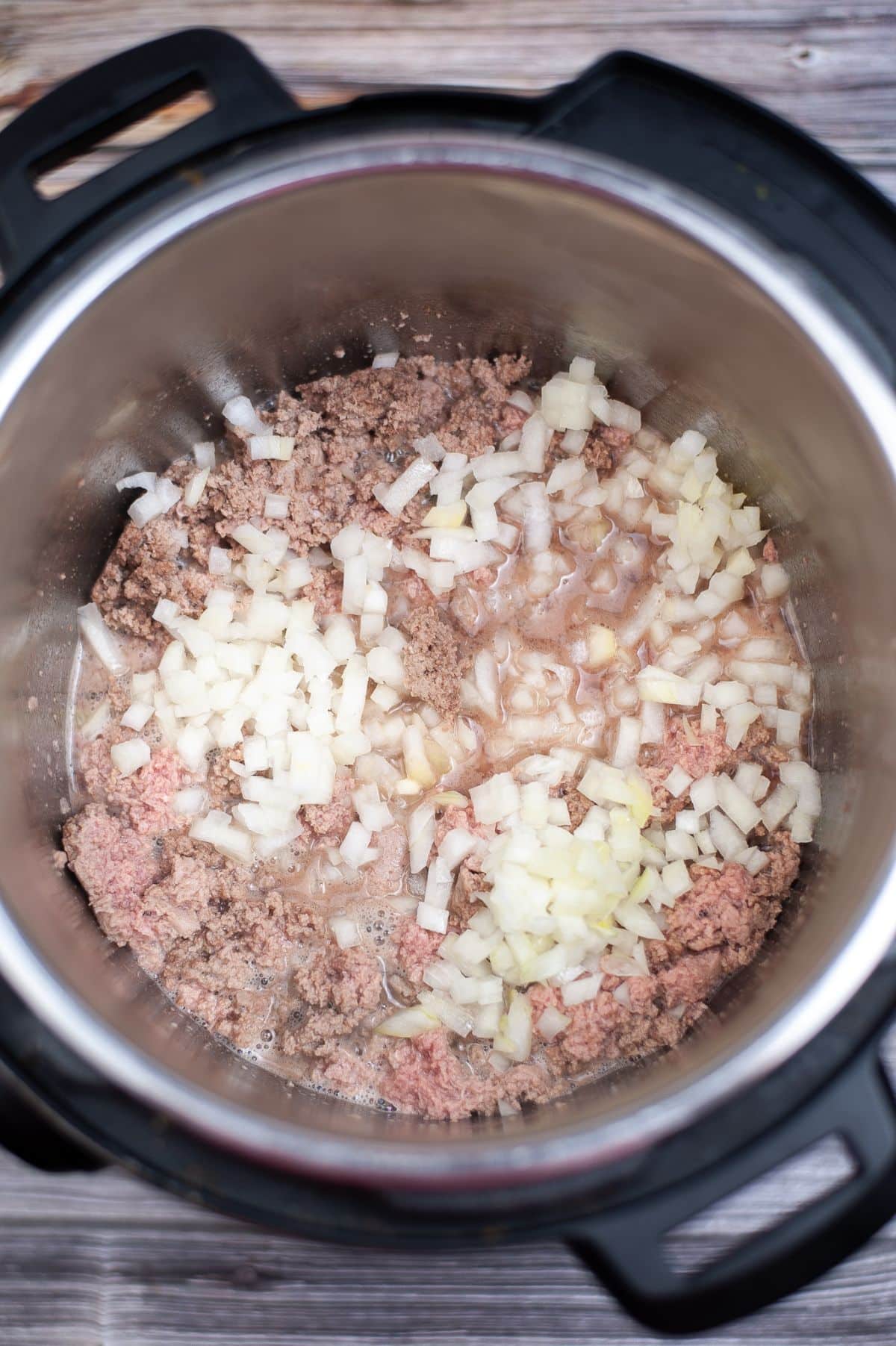 An Instant Pot filled with meat and onions being cooked into a delicious Cheeseburger Soup.
