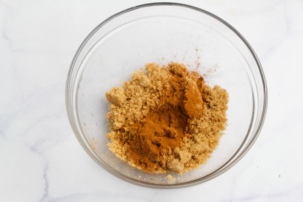 brown sugar, nutmeg and cinnamon in a glass bowl on a white countertop.