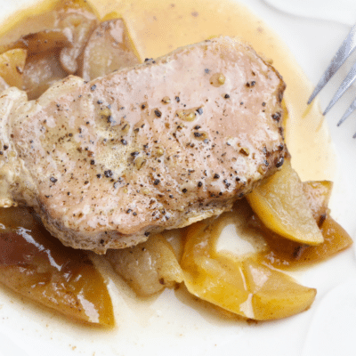 Instant Pot pork chops with apples on a white plate.