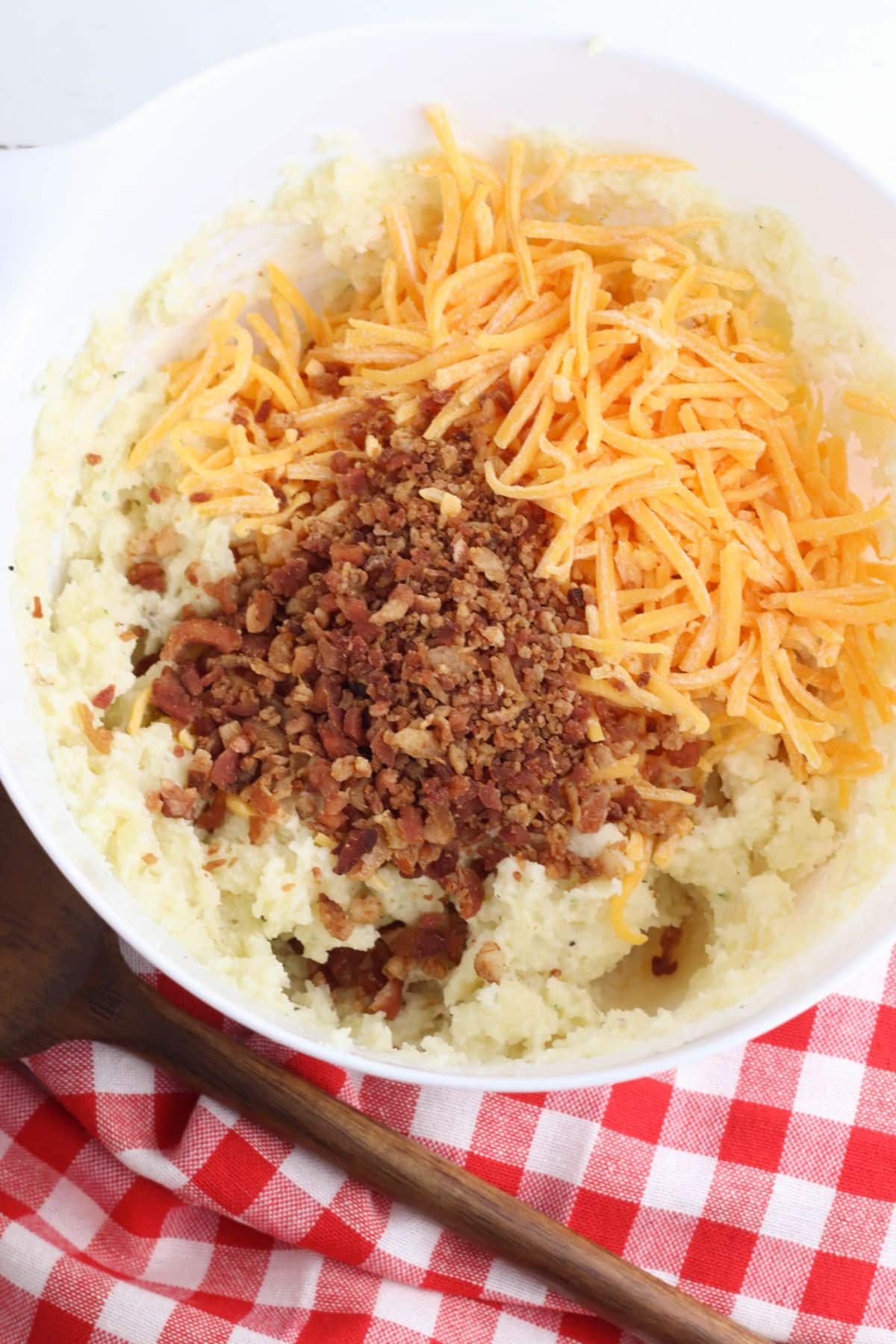 Potato mixture, shredded cheese and bacon in a mixing bowl.
