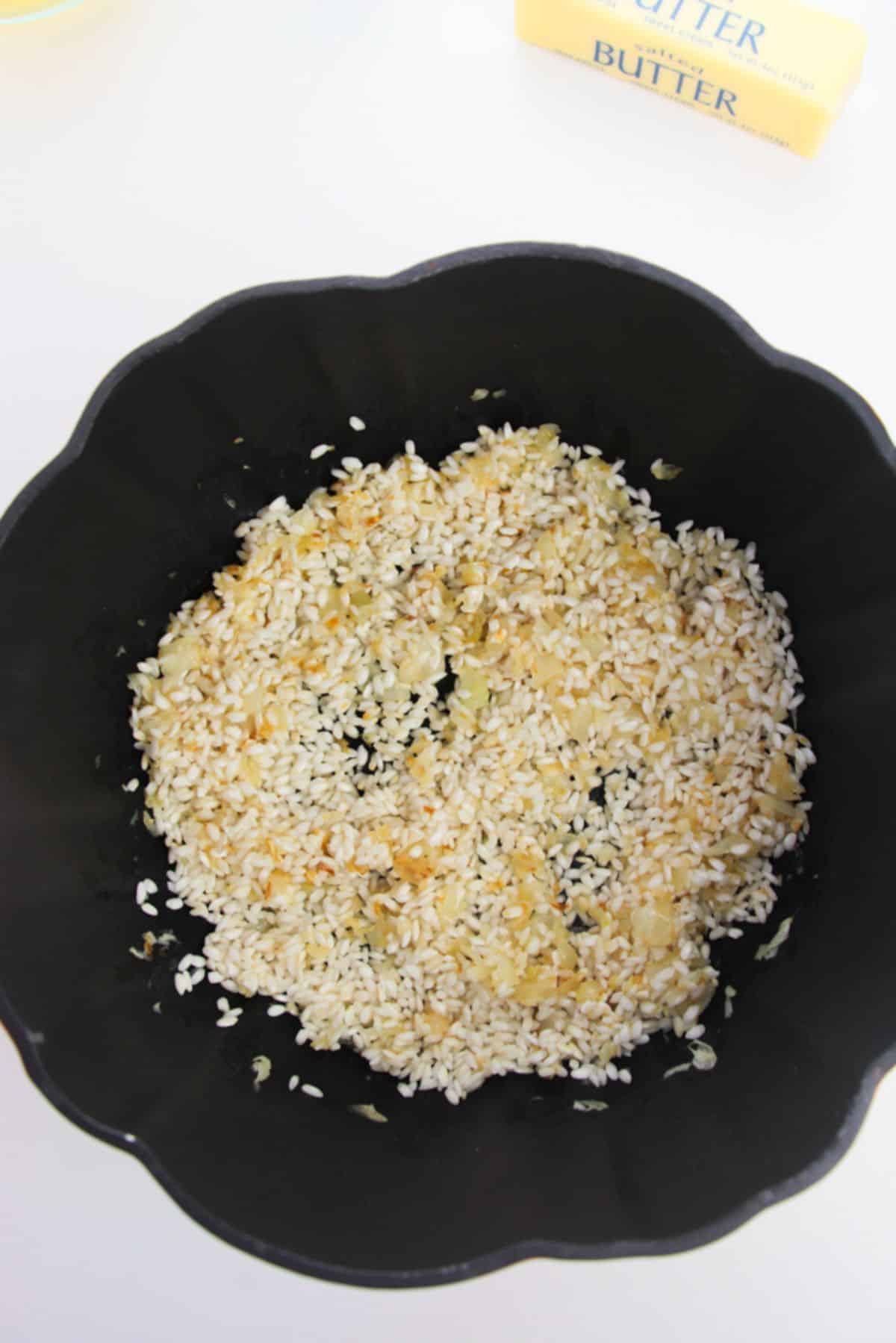 Arborio Rice is added to the stockpot with onion and garlic.