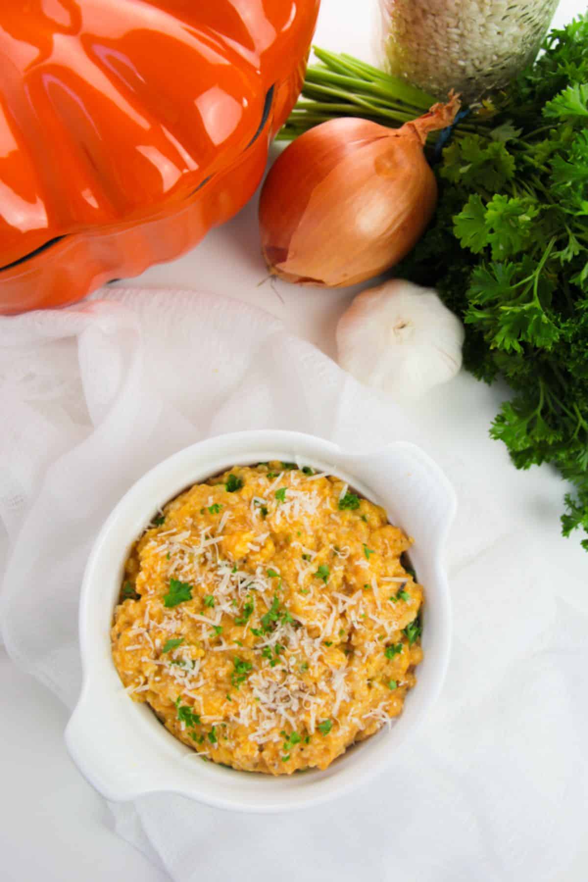 Overhead view of Pumpkin Risotto in a white bowl, garnished with parsley.