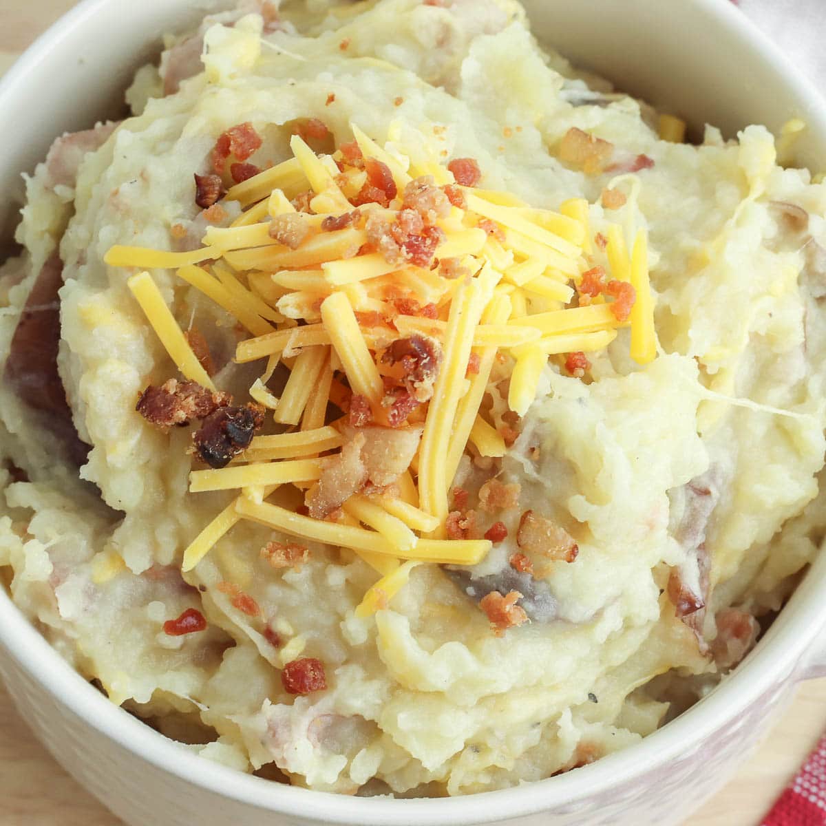 A bowl of mashed potatoes with bacon and cheese.