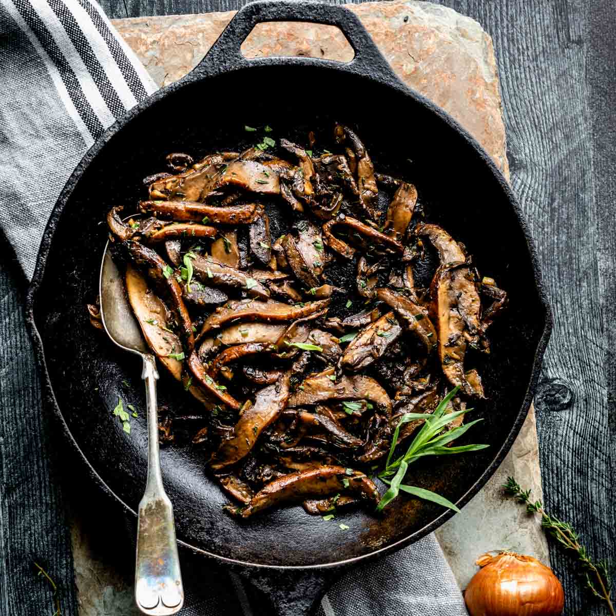 Roasted mushrooms in a skillet on a wooden board.