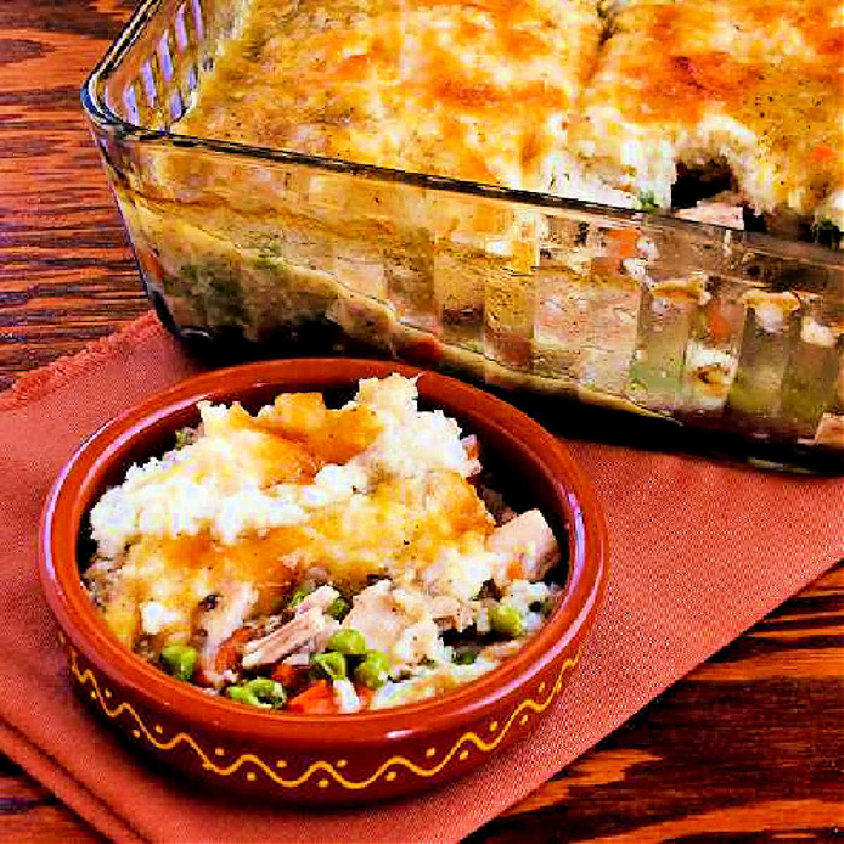 A casserole dish with mashed potatoes and peas.