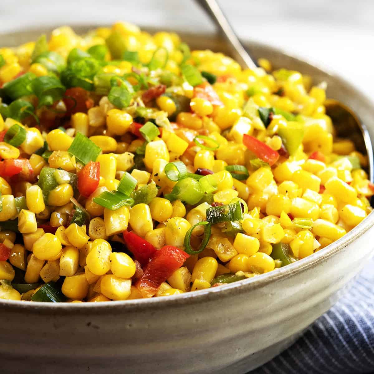 A bowl of corn salad with peppers and onions.