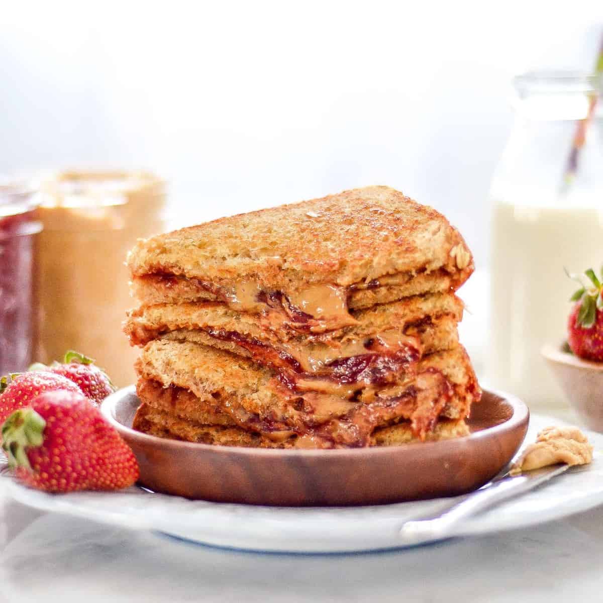 A stack of strawberry and peanut butter grilled cheese on a plate.