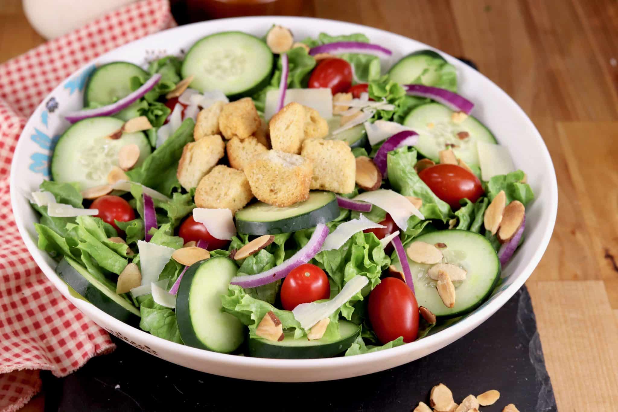 A bowl of salad with tomatoes, cucumbers and croutons.