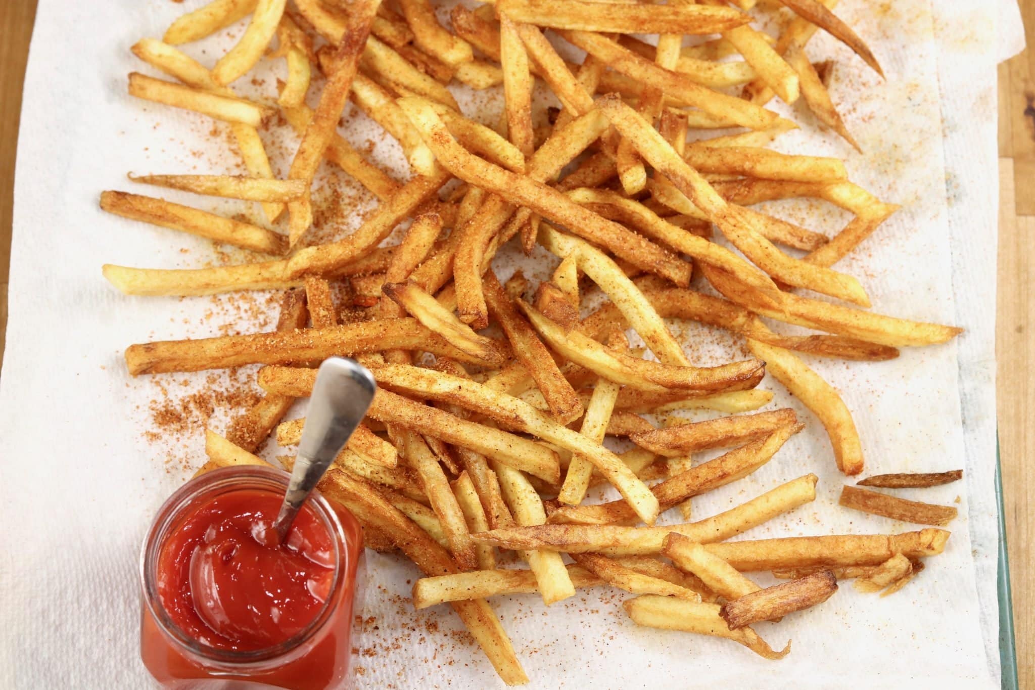 French fries on a baking sheet with ketchup.