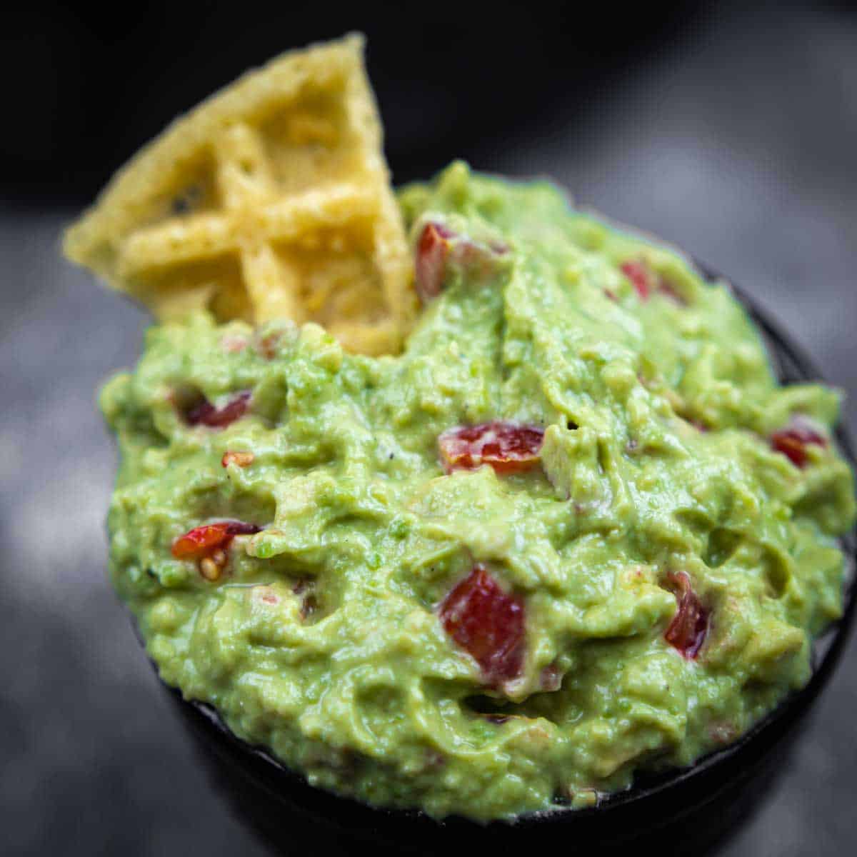 A bowl of guacamole with tortilla chips.