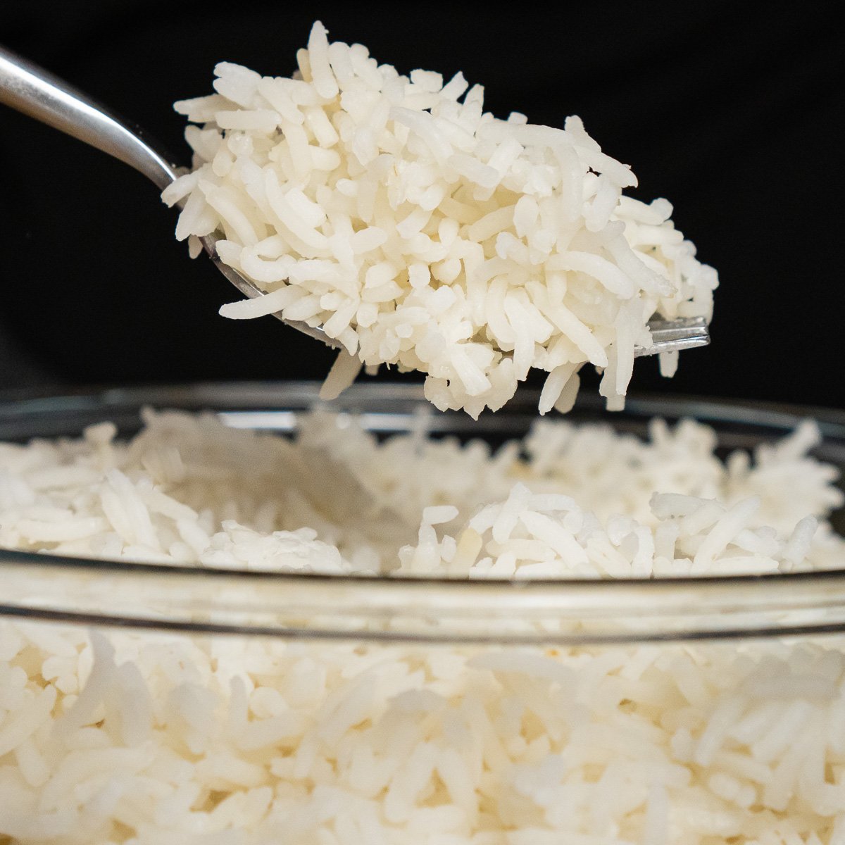 A spoon is being used to scoop rice out of a bowl.