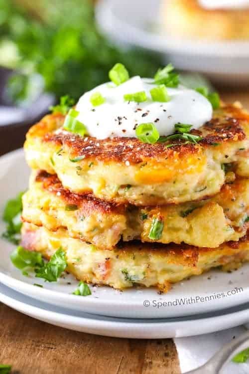 A stack of potato pancakes with sour cream and parsley.