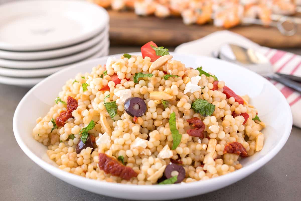 A bowl of couscous salad with feta and olives.
