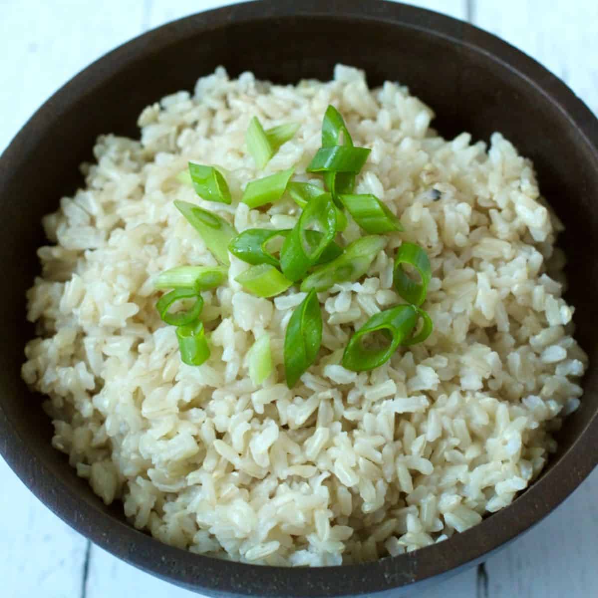 A bowl of brown rice with green onions.