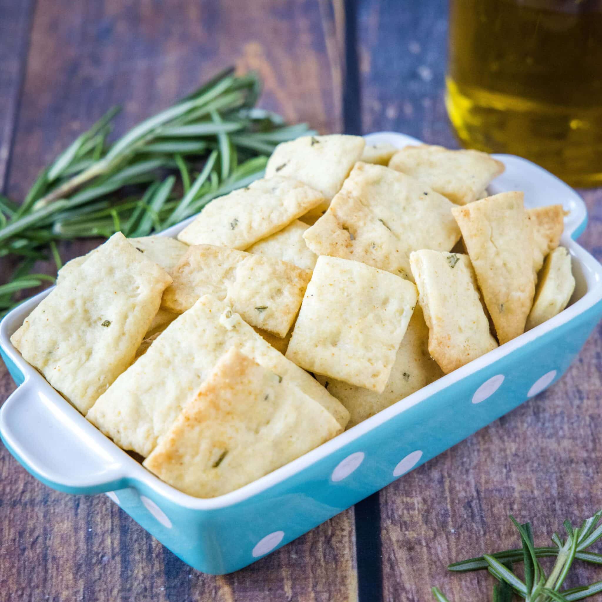 Rosemary crackers in a blue dish with sprigs of rosemary.