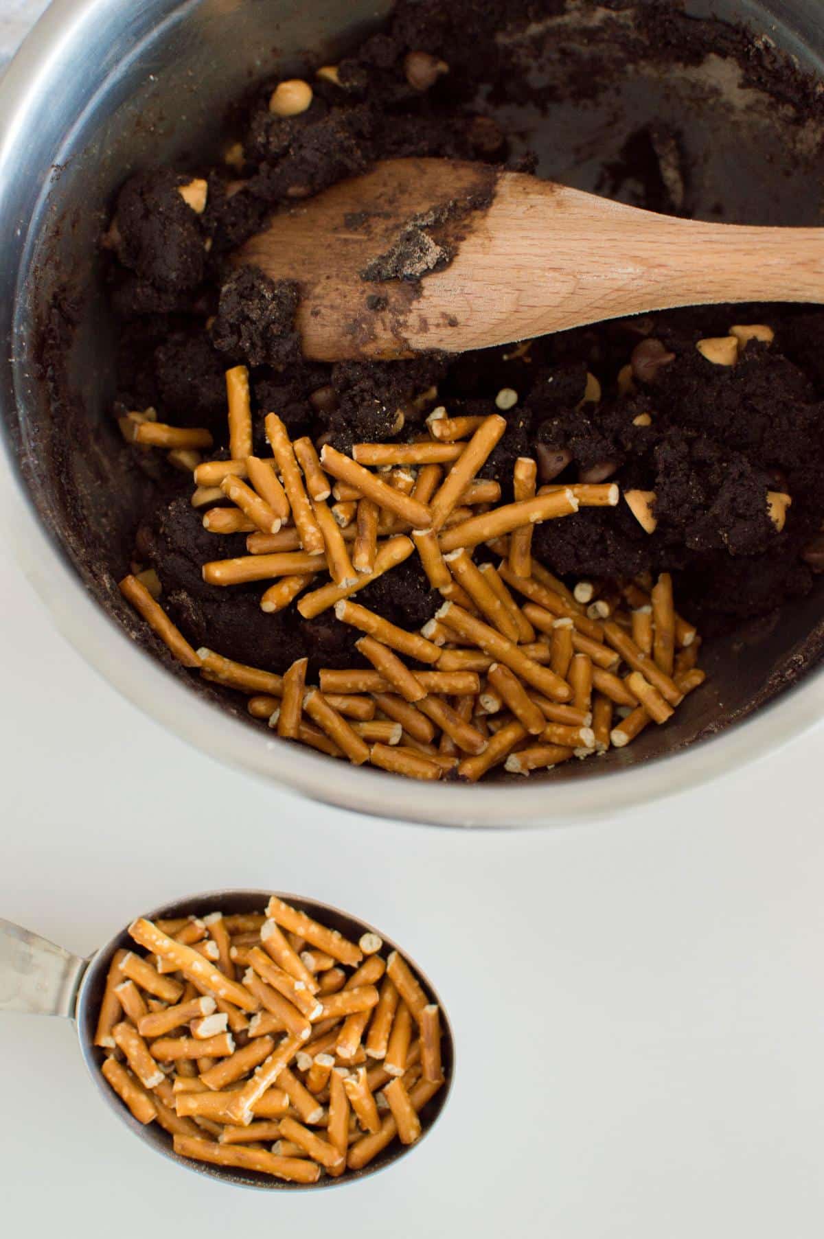 Pretzel sticks, caramel chips and chocolate chips are mixed in the batter using wooden spatula.