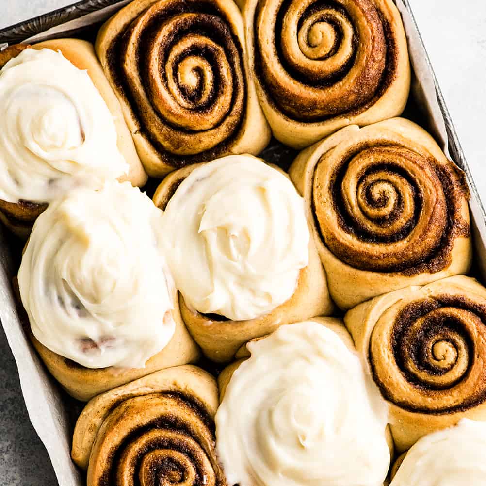Cinnamon rolls in a baking pan with icing.
