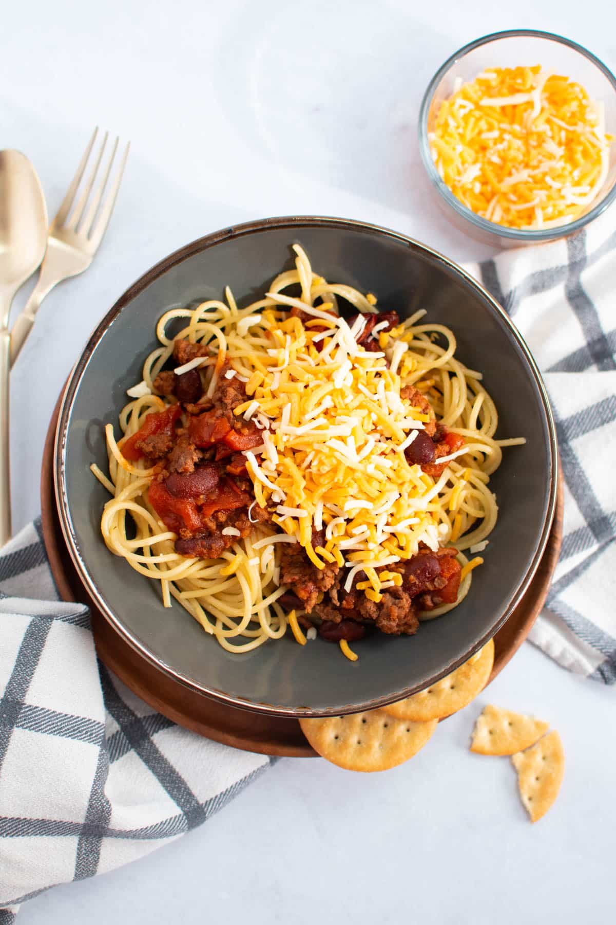 A bowl of spaghetti with meat, cheese and crackers.