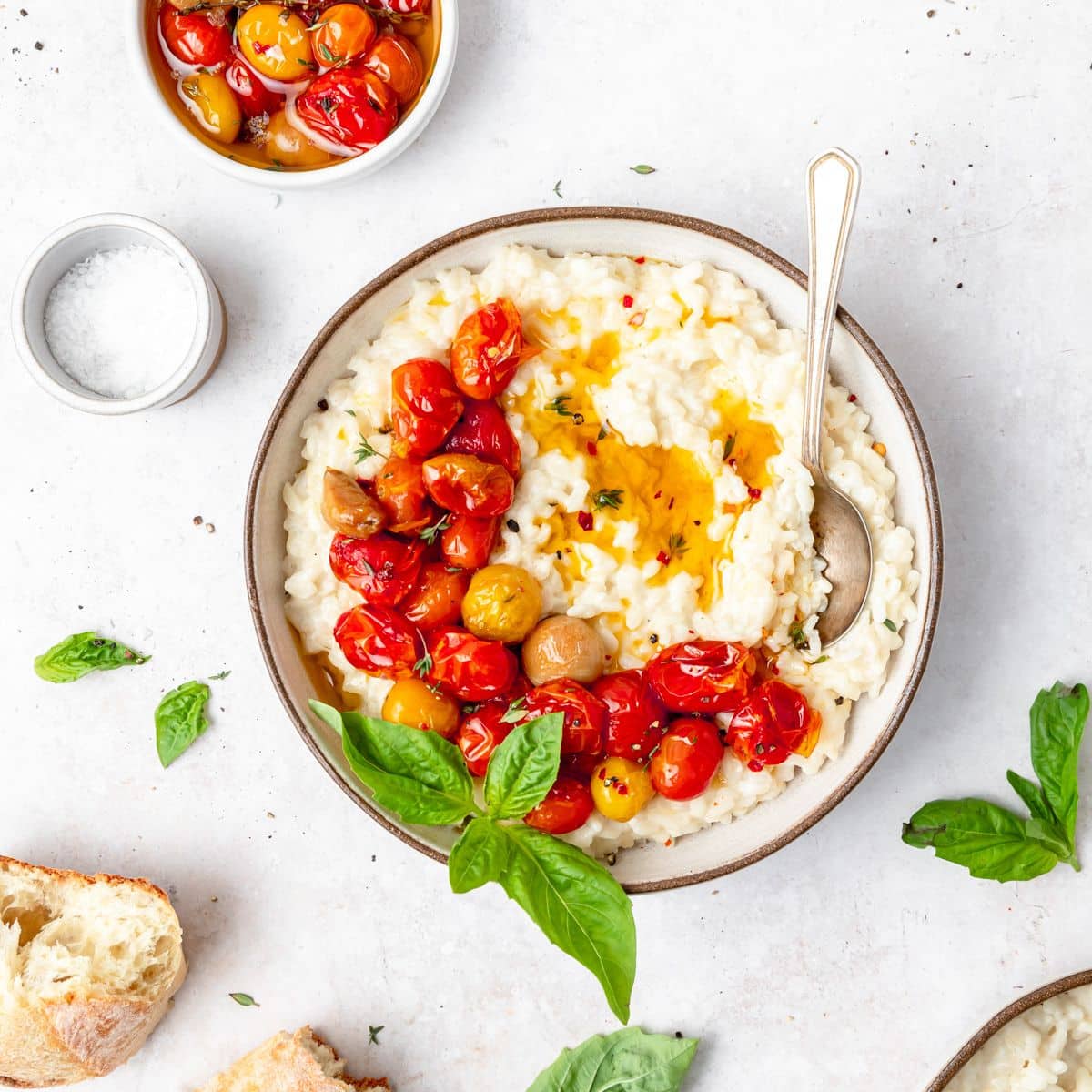 A bowl of hummus with tomatoes and basil.
