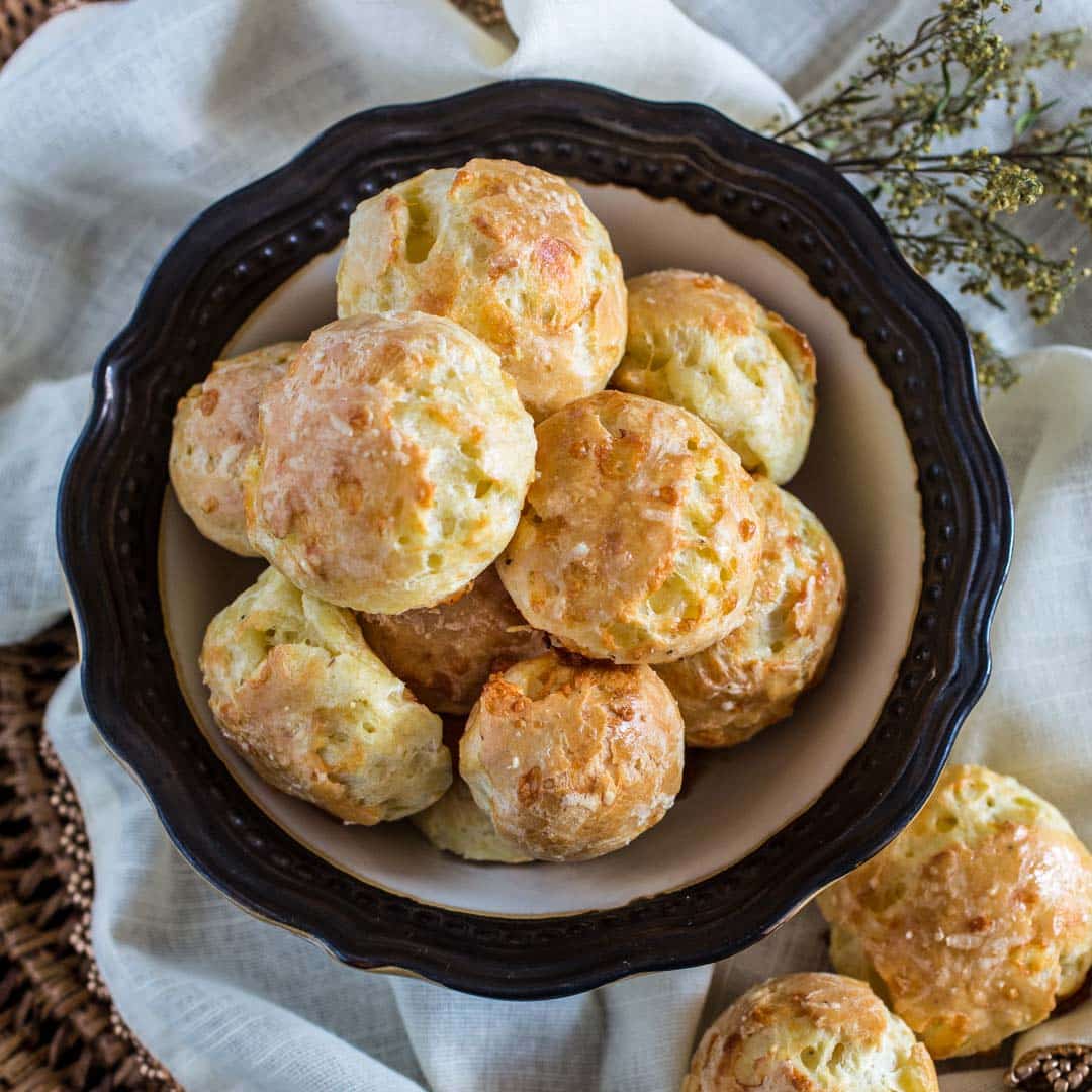 Cheesy biscuits in a bowl next to a wicker basket.
