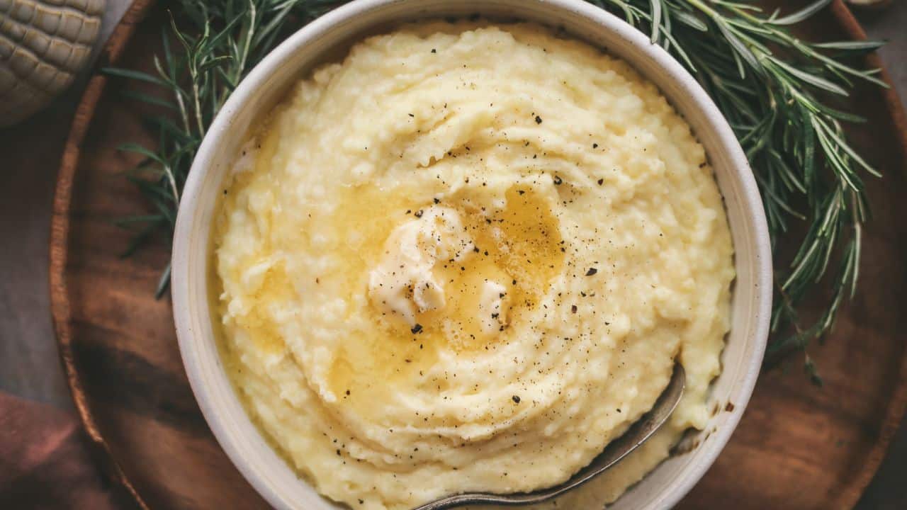 A bowl of mashed potatoes with sprigs of rosemary.