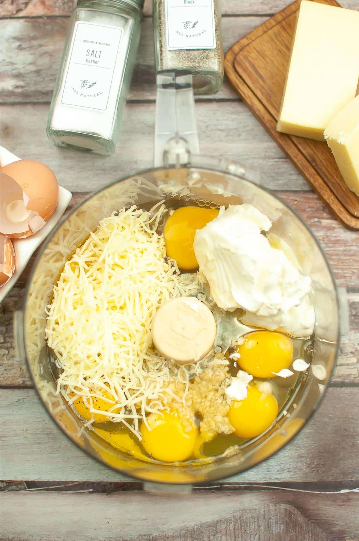 Eggs, minced garlic, cream cheese, sour cream, and Gruyere cheese in a food processor.