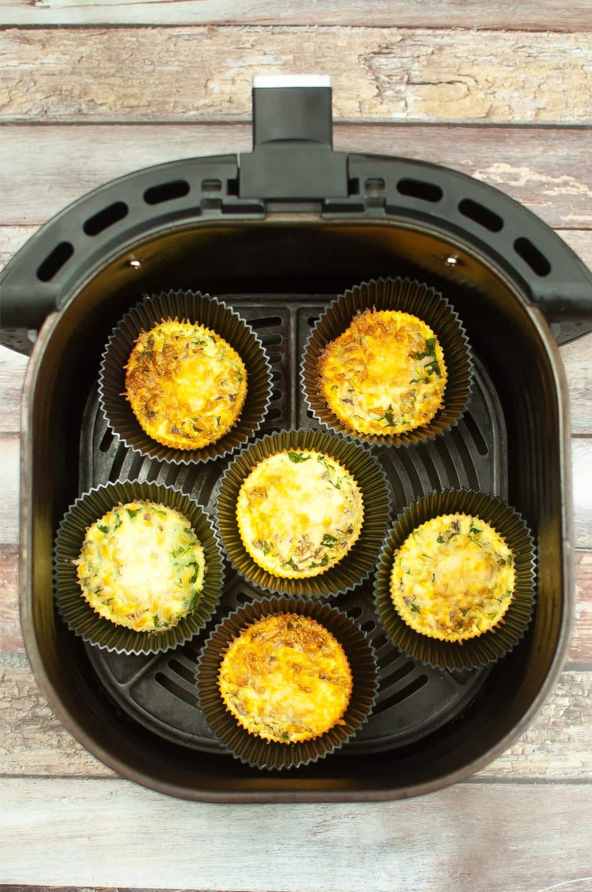 An air fryer filled with kale and mushroom egg bites.