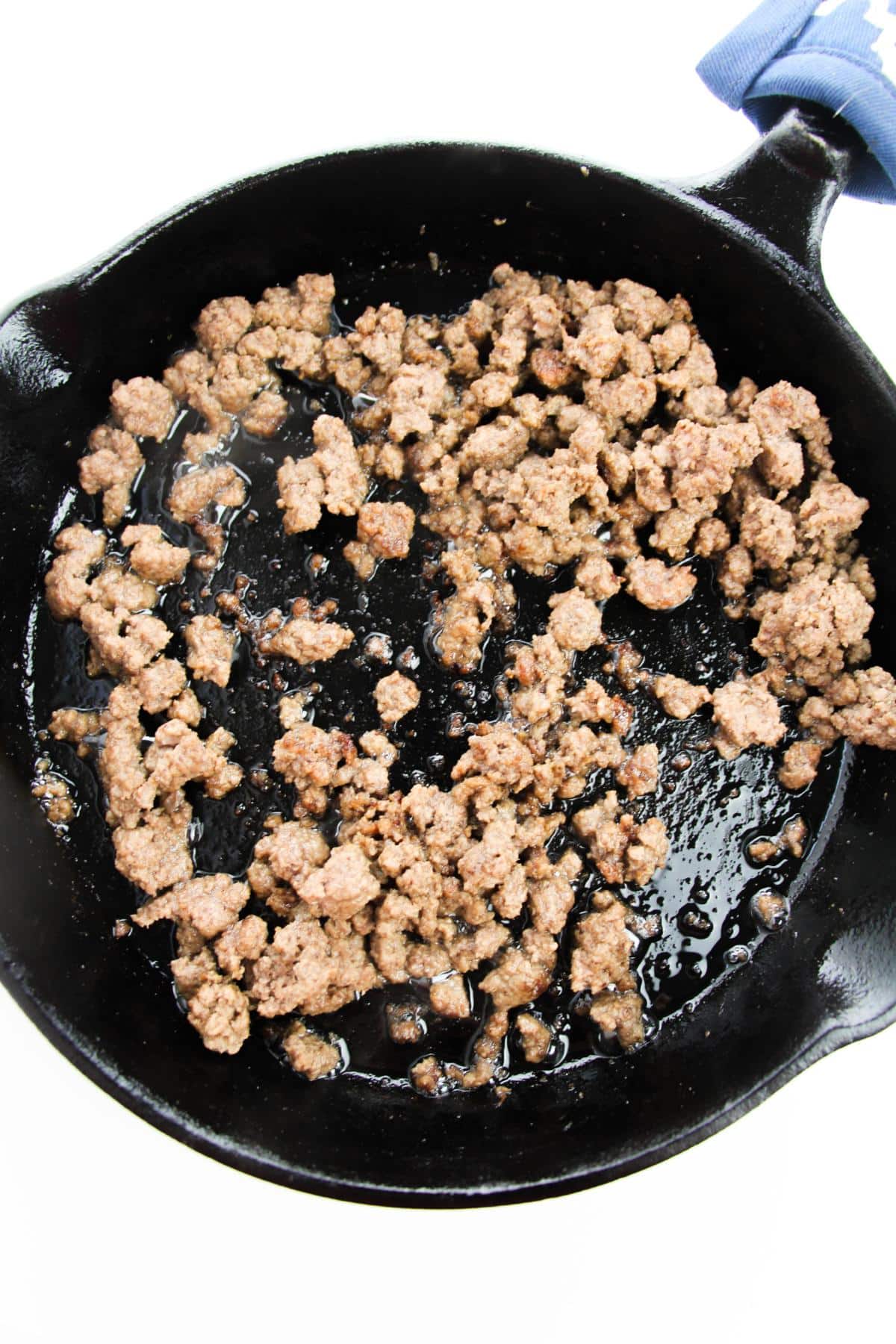 A cast iron frying pan with ground beef.