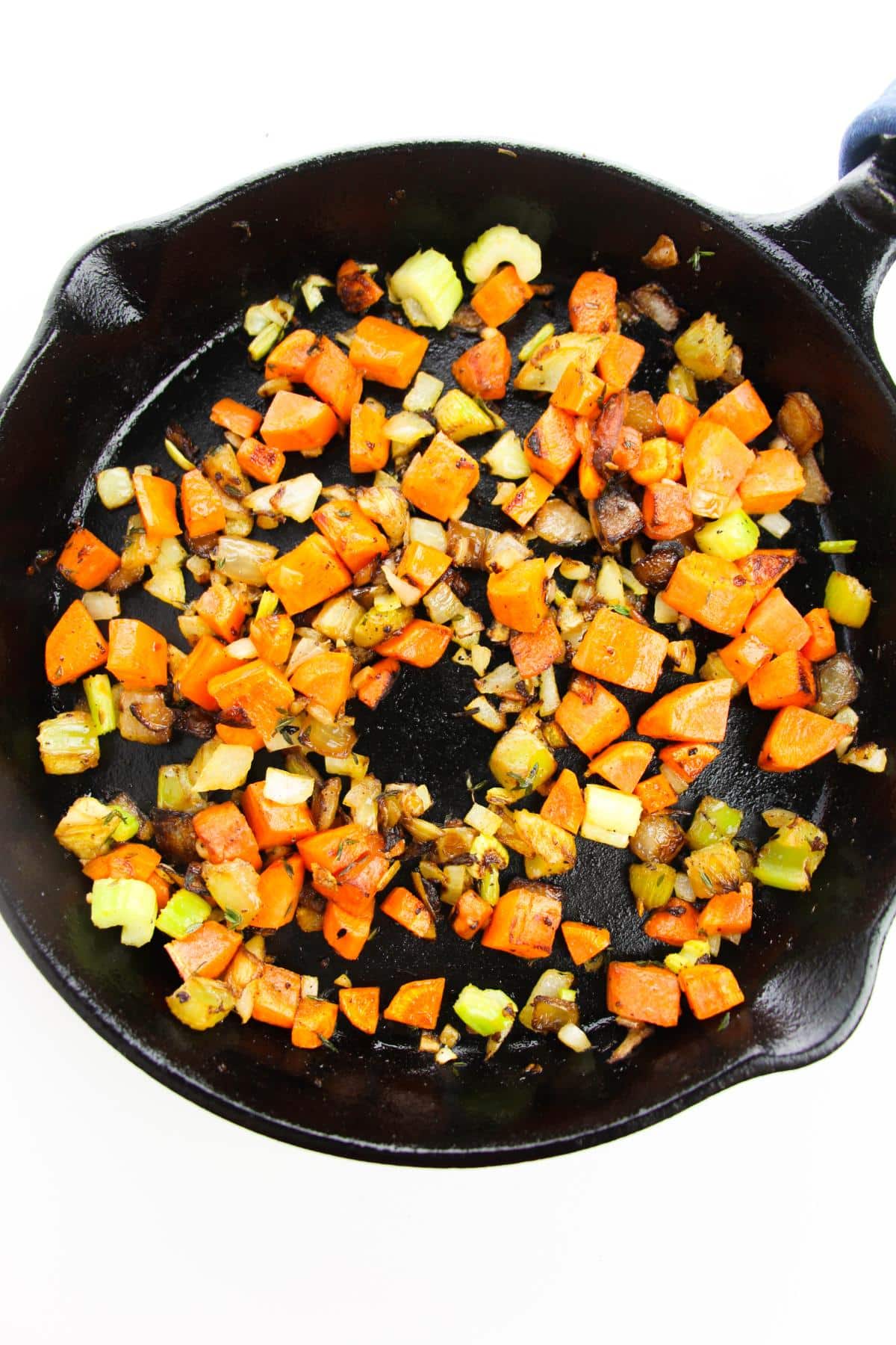 Cooked diced carrots, celery stalks, and onions in cast iron skillet.